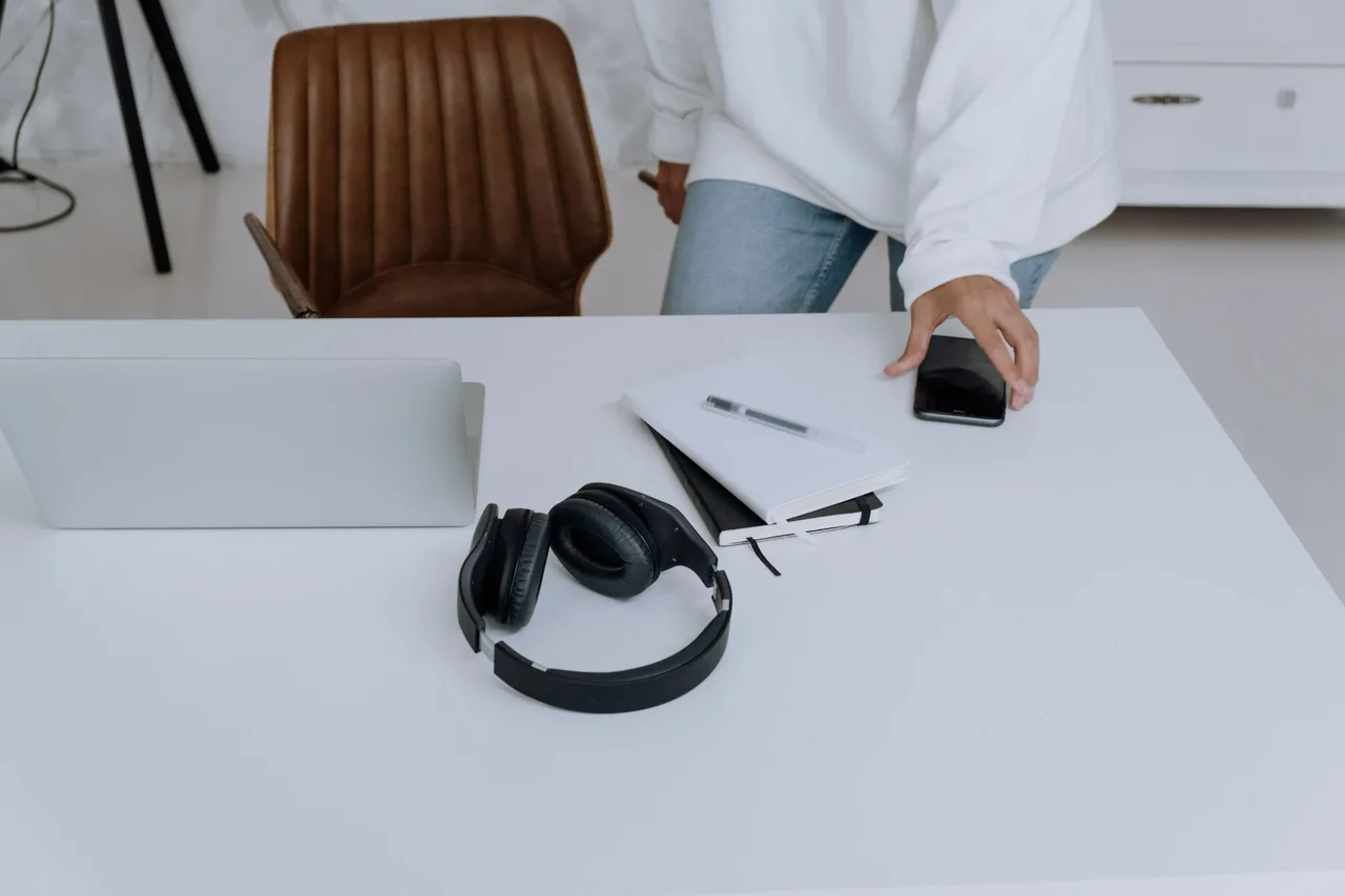 A workspace with laptop, headphones and a notebook