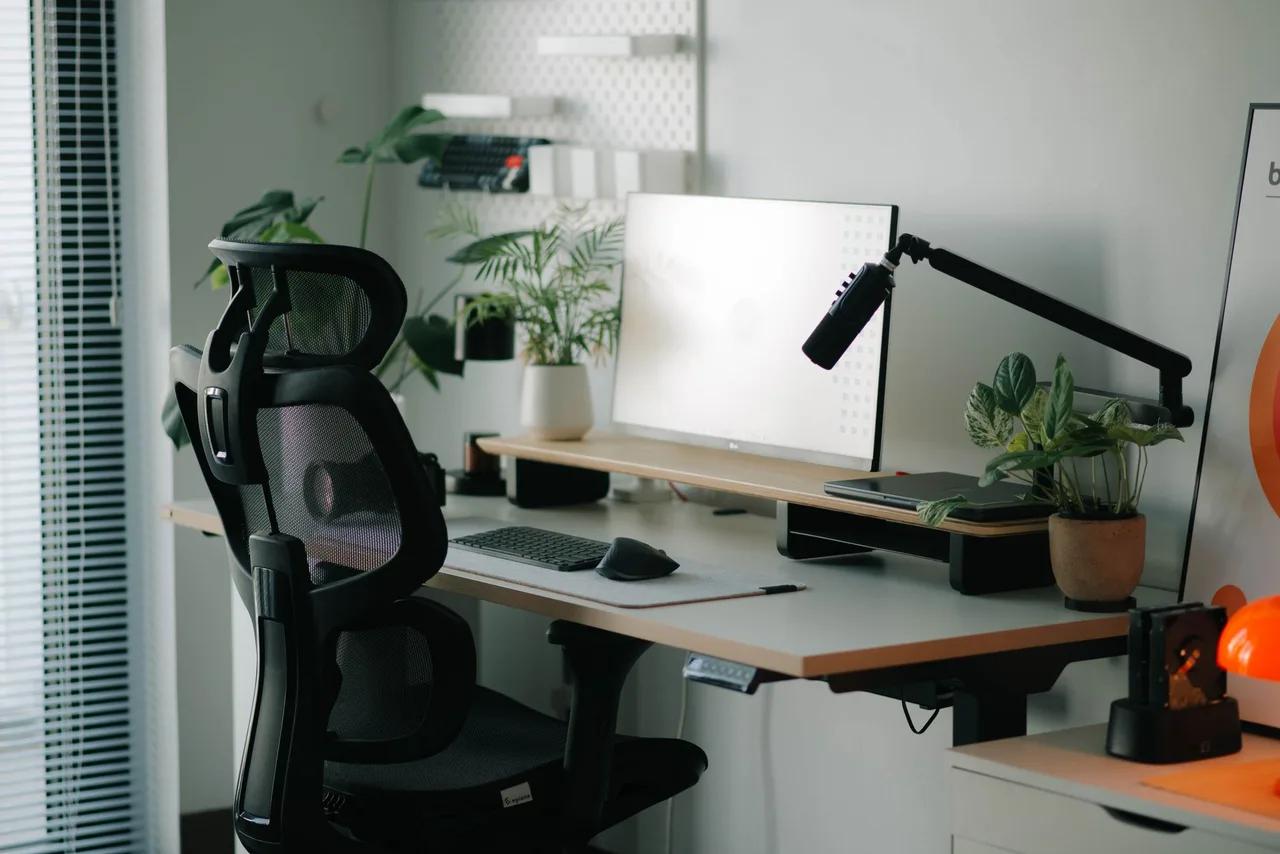 An office chair at a desk with plants and work accessories