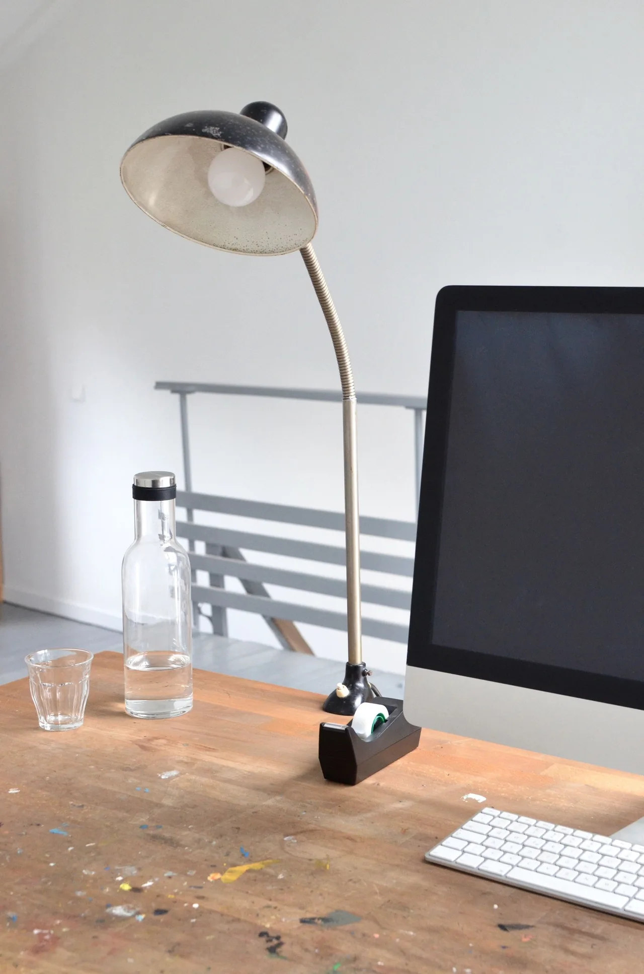 A desk with a task lamp, computer and water bottle